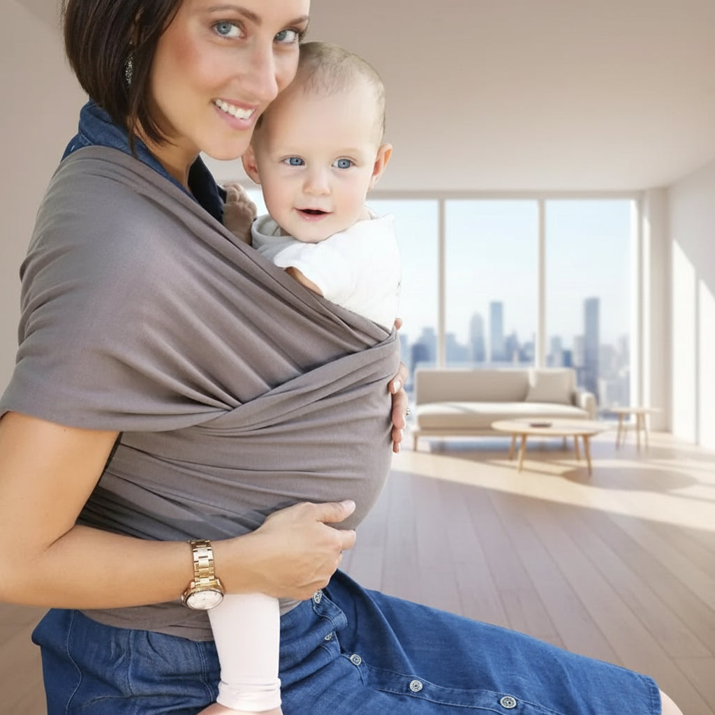 Woman holding a baby in a sling outdoors on a stone path.